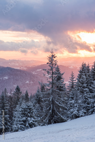 Malowniczy zachód słońca zimą w górach z widokiem na las photo