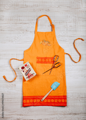 Orange apron with whisks, spatula and metal box