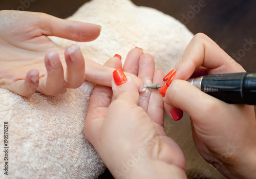 The master of the manicure saws and attaches a nail shape during the procedure of nail extensions with gel in the beauty salon. Professional care for hands.
