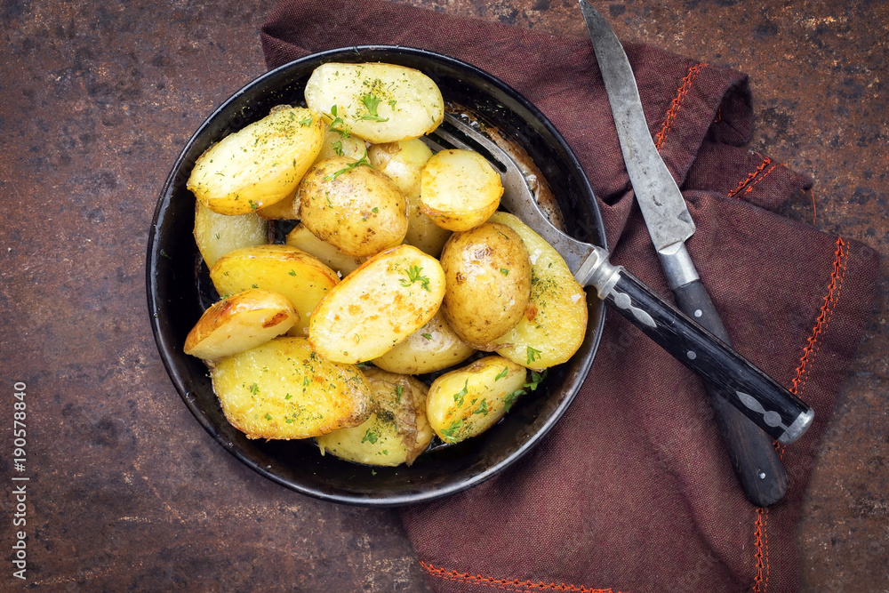 Roast Potatoes with herbs as top view in an iron cast pan Roast Potatoes with herbs as top view in an iron cast pan