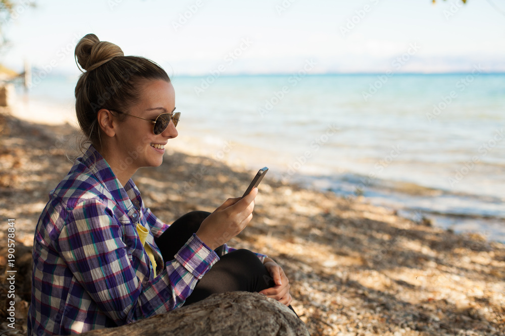 Happy smiling girl on vacation using phone