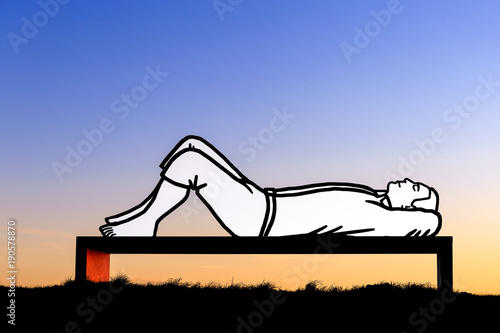 Bild auf Leinwand Lying man on a bench at sunset