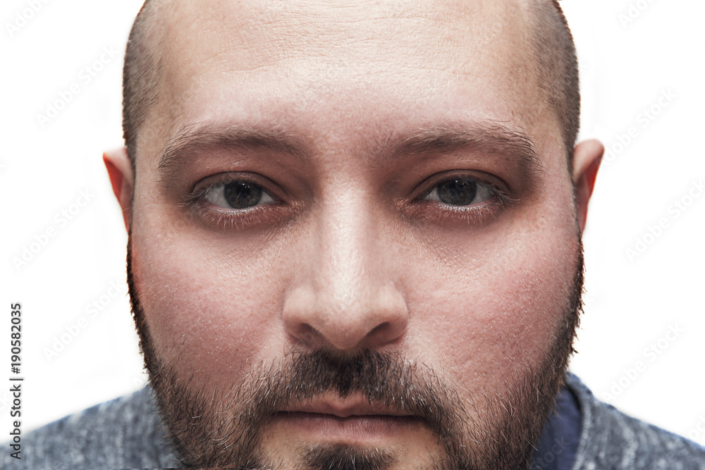 Obraz premium Young man with a bristle is staring or looking intently at the camera, close-up