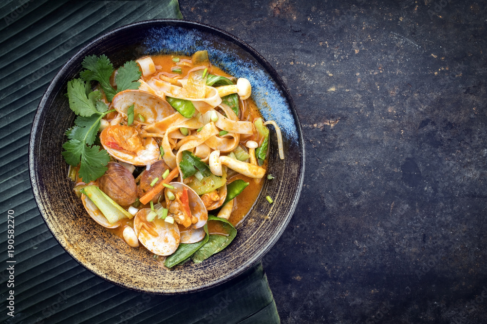 Traditional Thai kaeng phet red curry with clams and vegetable as top view in a bowl with copy space right Traditional Thai kaeng phet red curry with clams and vegetable as top view in a bowl with copy space right