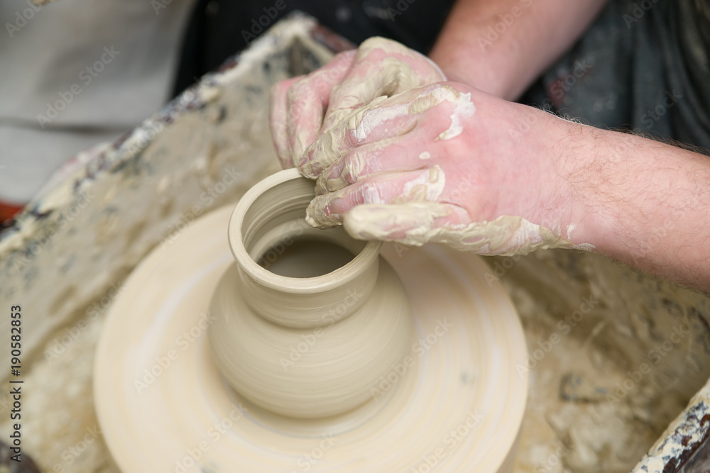 Hands of young potter kneading clay