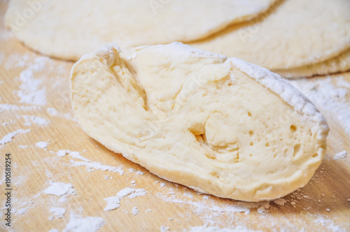 Raw wheat yeast dough rolled out into flat cakes on a table