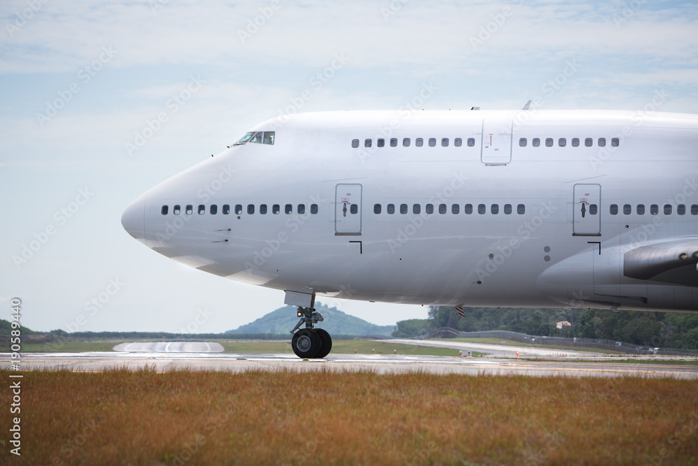 White airplane is taxiing to take off on sunny day / wide-body aircraft on  the runway is getting ready to take off, close-up/ Fuselage of the  passenger double-decker aircraft close-up Stock Photo