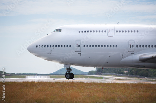 White airplane is taxiing to take off on sunny day / wide-body aircraft on the runway is getting ready to take off, close-up/ Fuselage of the passenger double-decker aircraft close-up