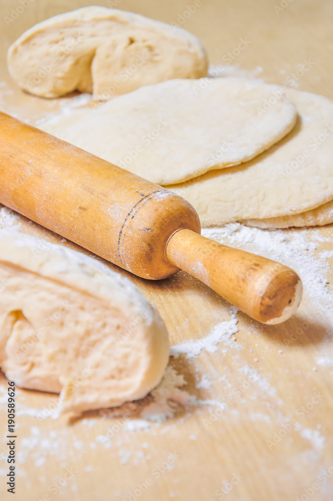Rolled wheat dough and rolling pin on a wooden table Rolled wheat dough and rolling pin on a wooden table