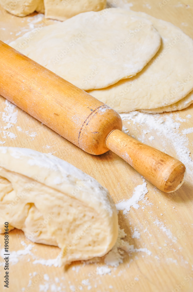 Rolled wheat dough and rolling pin on a wooden table Rolled wheat dough and rolling pin on a wooden table