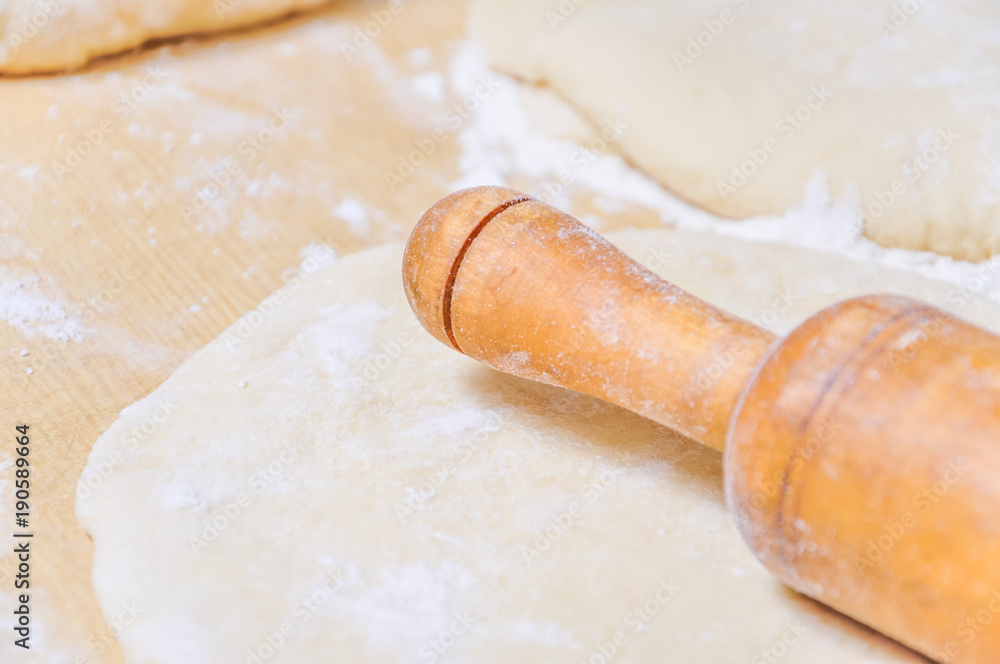 Rolled wheat dough and rolling pin on a wooden table Rolled wheat dough and rolling pin on a wooden table