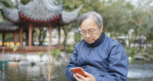 Canvas Print Senior man watching on smart phone in china