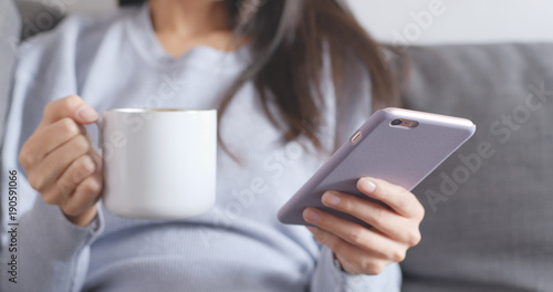 Woman use of smart phone and holding hot coffee