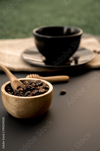 Top view a black cup of coffee americano and coffee bean grain on sack fabric put on black wood table background include copyspace for add text or graphic