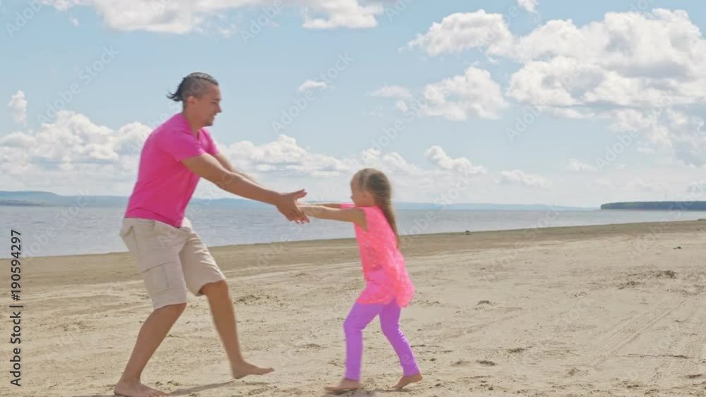 Happy family father turns baby son on the beach. A man is spinning a girl around him. He rotates it above the ground. Happy family father turns baby son on the beach. A man is spinning a girl around him. He rotates it above the ground.