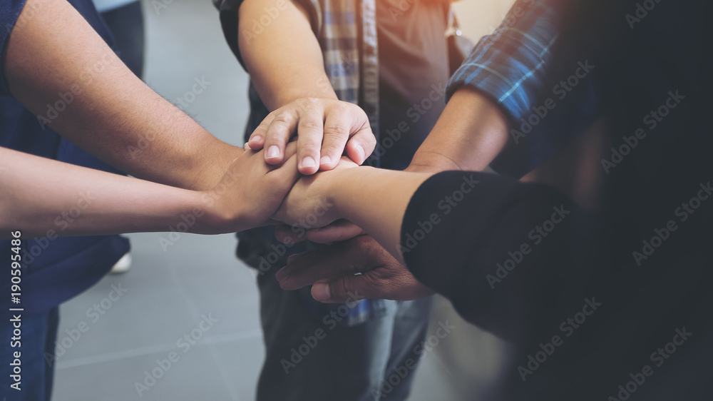 Closeup image of business team standing and joining their hands together in office Closeup image of business team standing and joining their hands together in office
