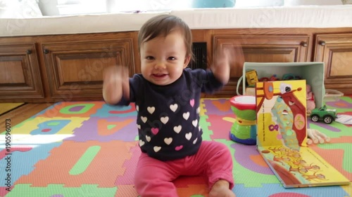 Cute baby dancing and flapping arms. Happily playing and laughing on floor with play mat.