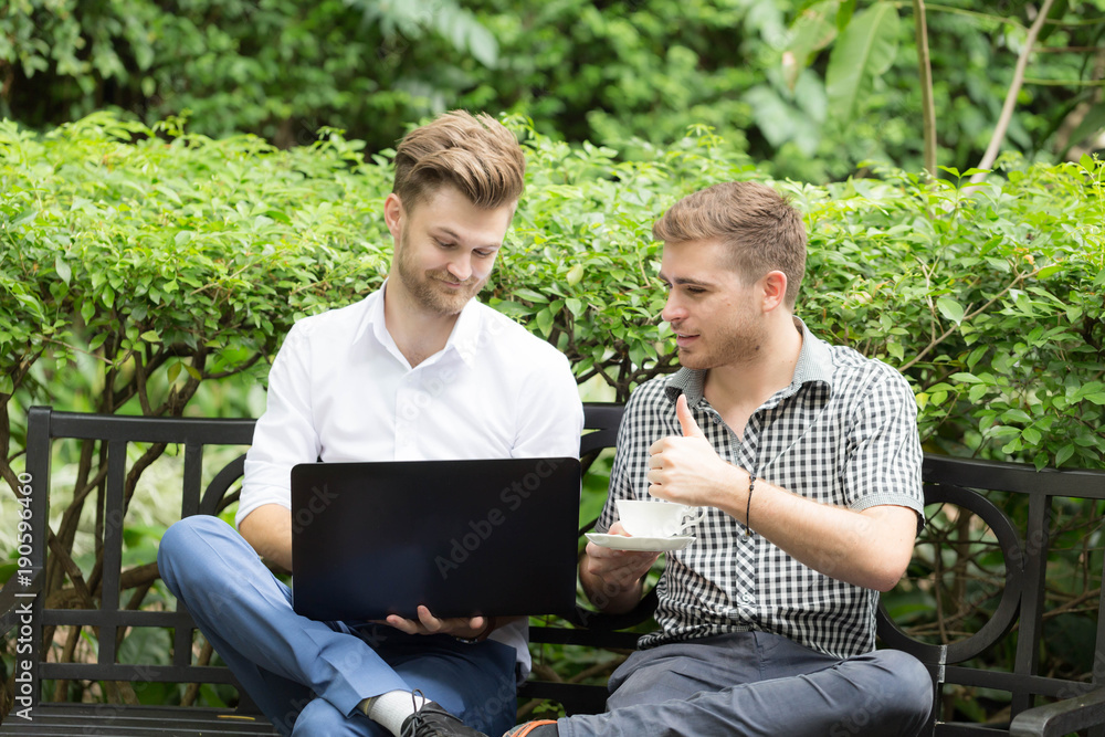Two business man looking in laptop and showing thumbs up Two business man looking in laptop and showing thumbs up