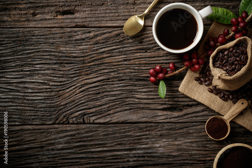 Top view mockup on wood background with a cup of coffee and red ripe coffee beans. Top view with copy space, flat lay.