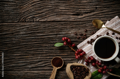 Top view mockup on wood background with a cup of coffee and red ripe coffee beans. Free space for your text. © Kanitta