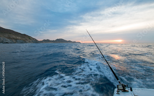 Early morning sunrise view of fishing rod on charter fishing boat on the Pacific side of Cabo San Lucas in Baja California Mexico BCS