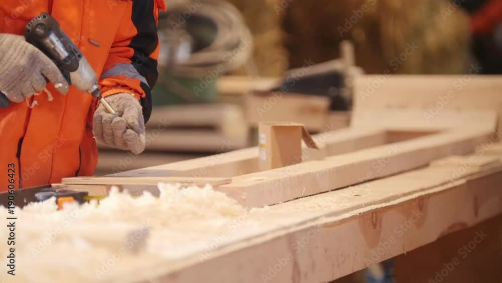 Construction workers measureing and screwing a bolt in wooden detail with screwdriver Construction workers measureing and screwing a bolt in wooden detail with screwdriver