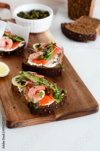 Smorrebrod, traditional Danish open sanwiches, dark rye bread with salmon, avocado, shrimp and micro-green.