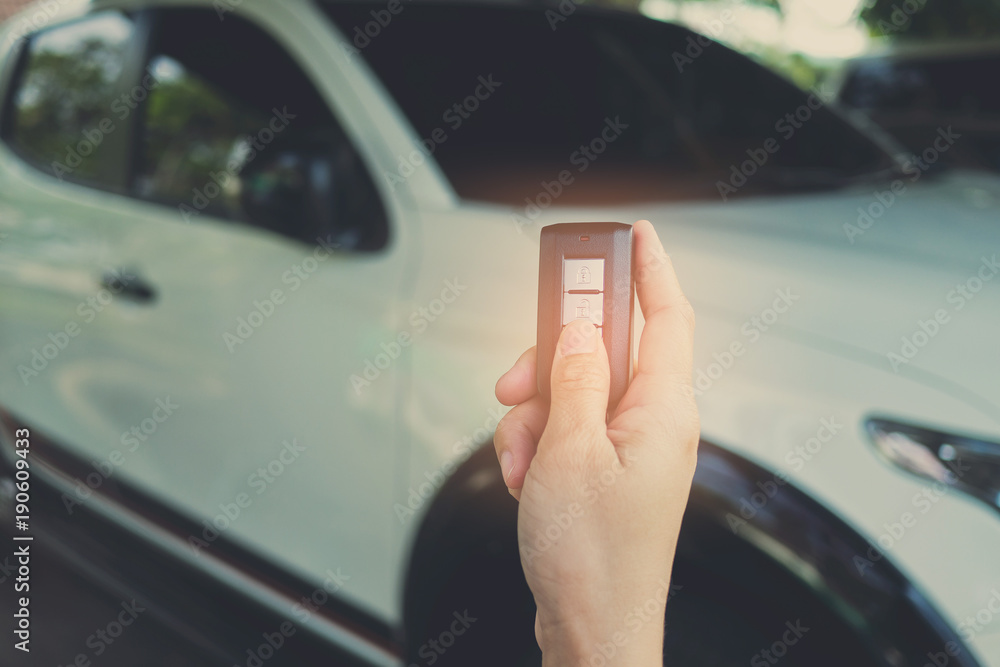 press buttom to unlock door . selective focus of Hand presses on the remote control car. car remote on hand with car background. remote control car 