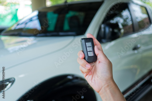 press buttom to unlock door . selective focus of Hand presses on the remote control car. car remote on hand with car background. remote control car 