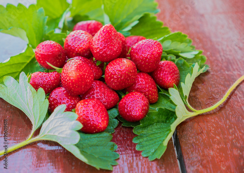 Fresh strawberries with strawberry leaves on rwooden table photo