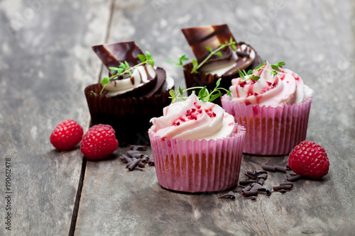 Chocolate cupcakes with fresh raspberries and cream on wooden table