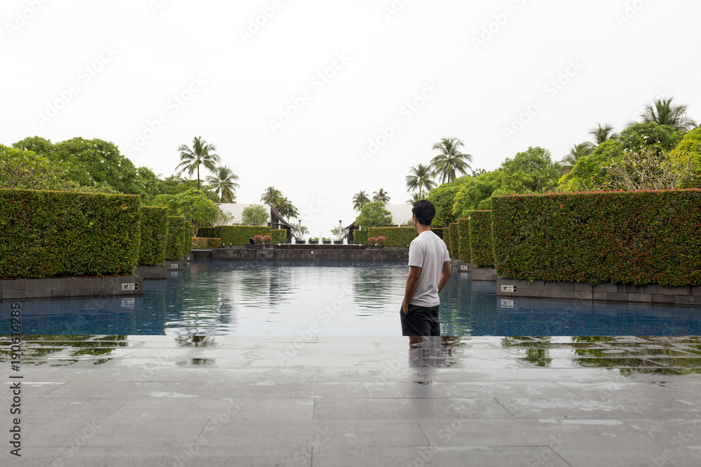Man standing at swimming pool of luxury hotel