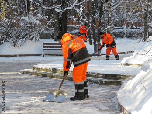 Snow removal in Moscow. Communal services workers in uniform with a shovel clears snow in winter