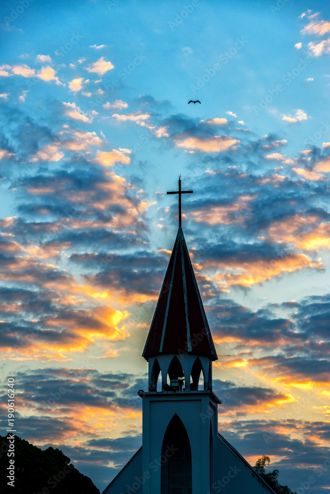 Obraz premium A silhouette of a church steeple in sunrise.