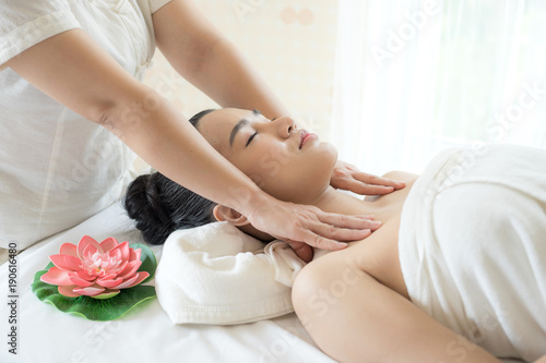 Beautiful and healthy young woman relaxing with face and shoulder massage at beauty spa salon
