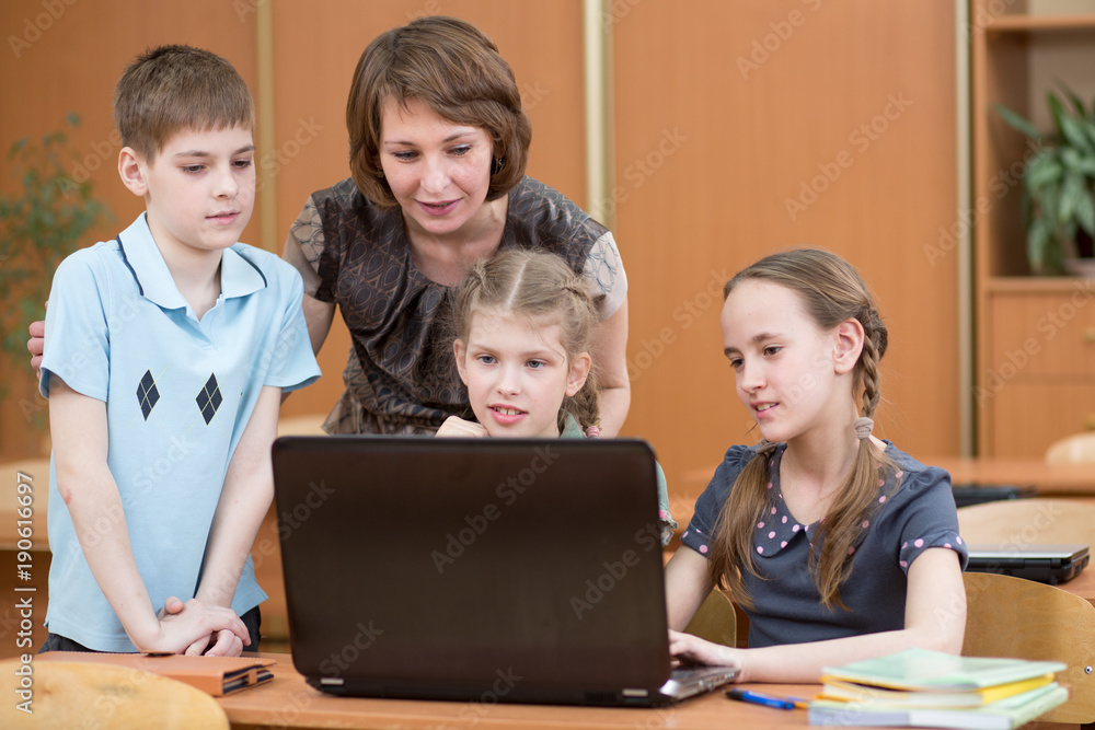 School kids and teacher at laptop in the classroom School kids and teacher at laptop in the classroom