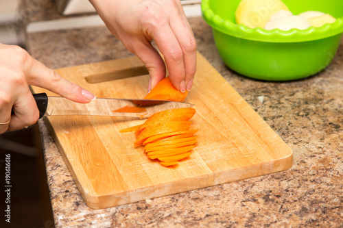 A girl is cutting a carrot with a knife on the board