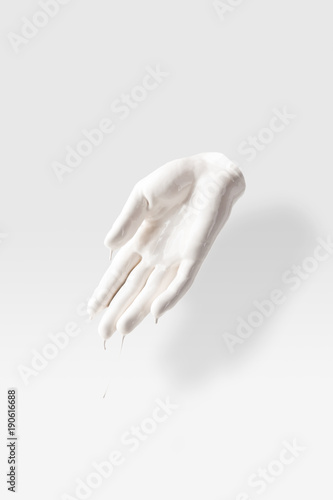abstract sculpture in shape of human palm in white paint on white photo