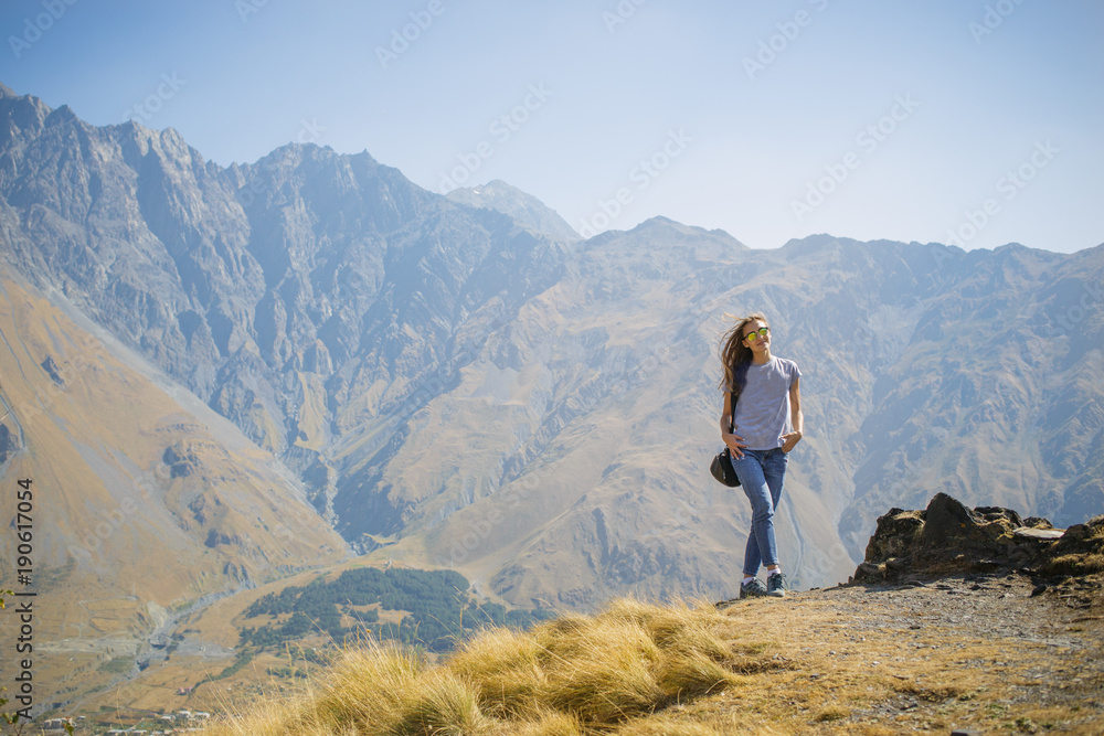 Hiker with backpack standing on top of the mountain and enjoying valley view at sunrise Hiker with backpack standing on top of the mountain and enjoying valley view at sunrise