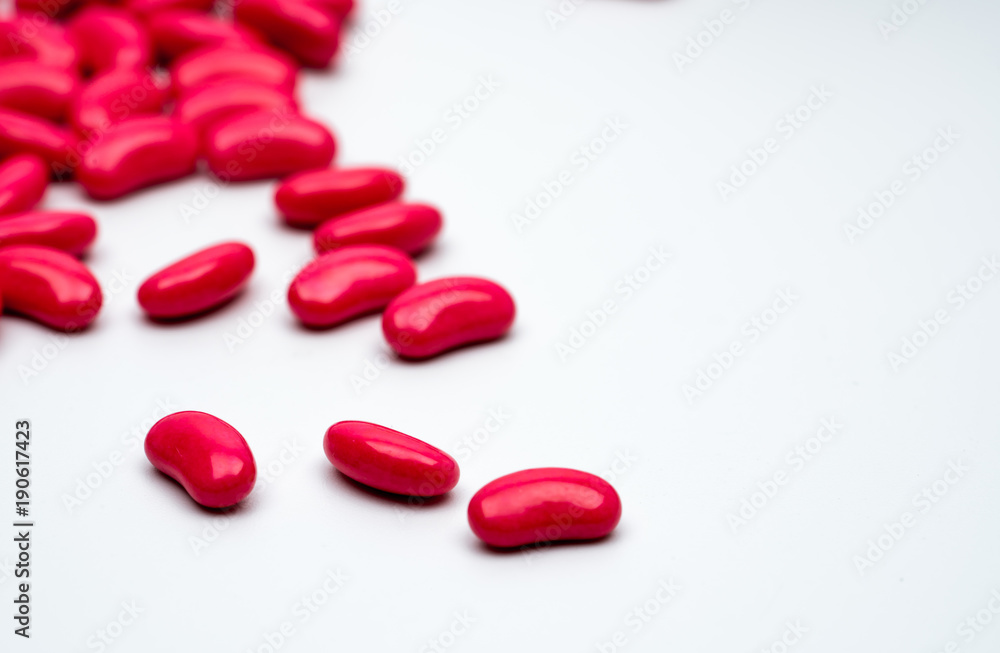 Red kidney shape sugar coated tablet pills isolated on white background with copy space for text. Red kidney shape sugar coated tablet pills isolated on white background with copy space for text.