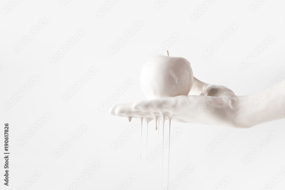 Fototapeta cropped image of girl in white paint holding apple isolated on white