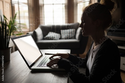Wallpaper Mural Side view of woman using a laptop at home Torontodigital.ca