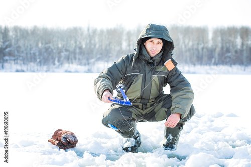 A young man is fishing from a hole on ice. Winter fishing