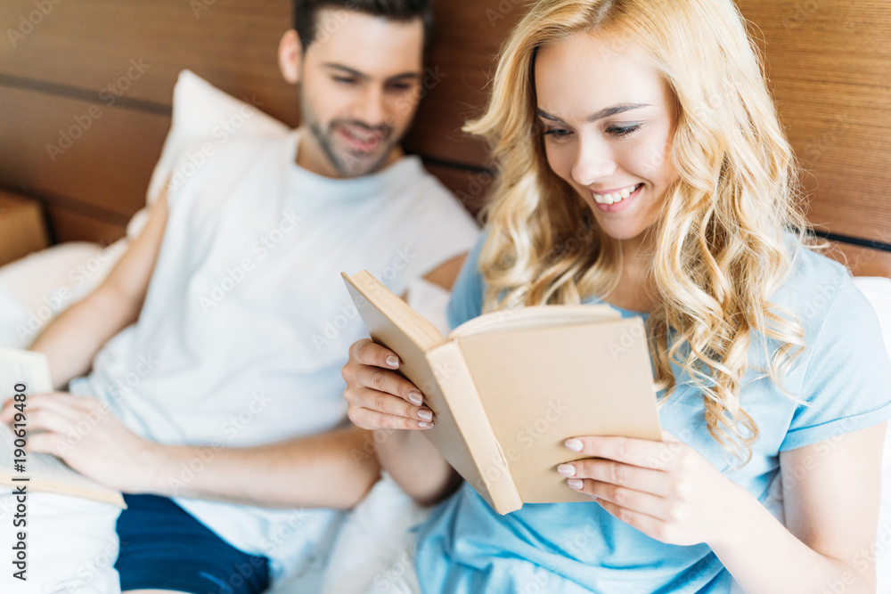 smiling couple reading books in bed smiling couple reading books in bed