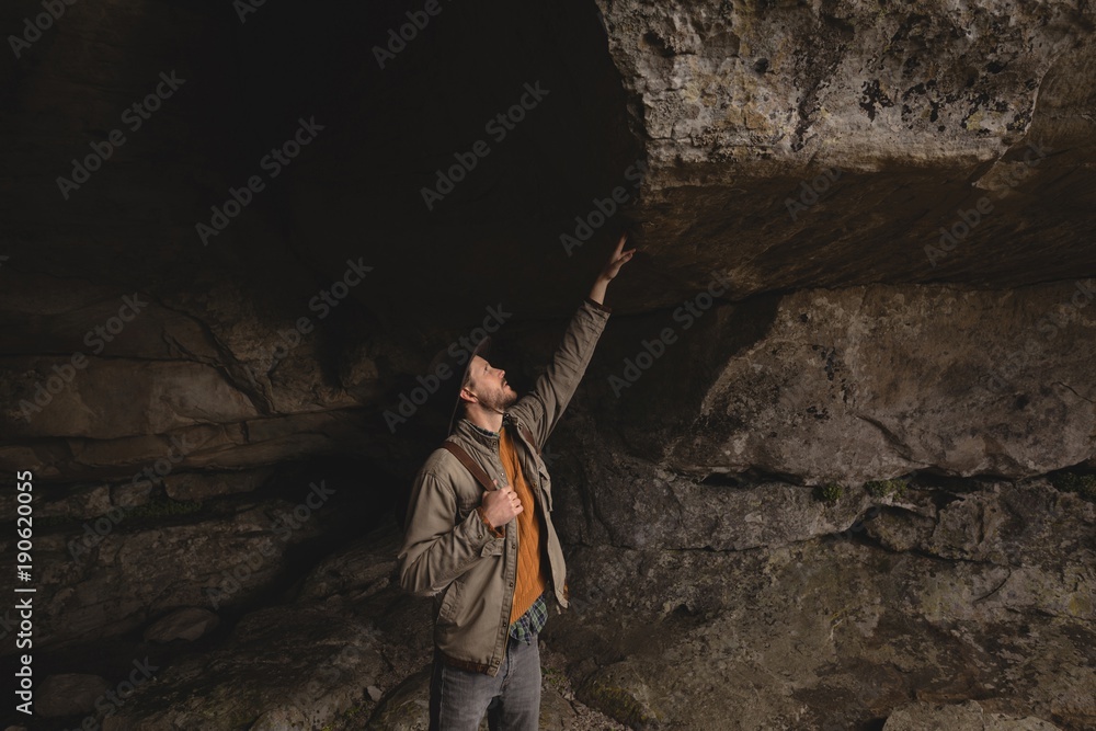 Hiker inspecting rocks in a cave Hiker inspecting rocks in a cave