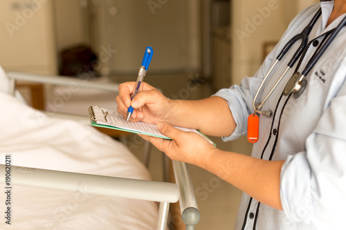 Woman doctor writing medical details of patient photo