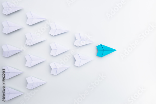 Leadership concept with blue paper plane leading among white.