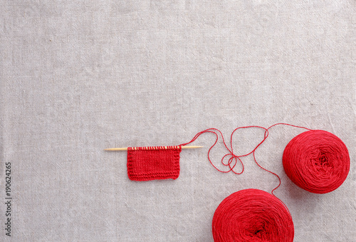 Wool yarn color of red with wooden knitting needles.