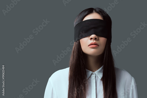 young woman wearing black blindfold isolated on grey photo