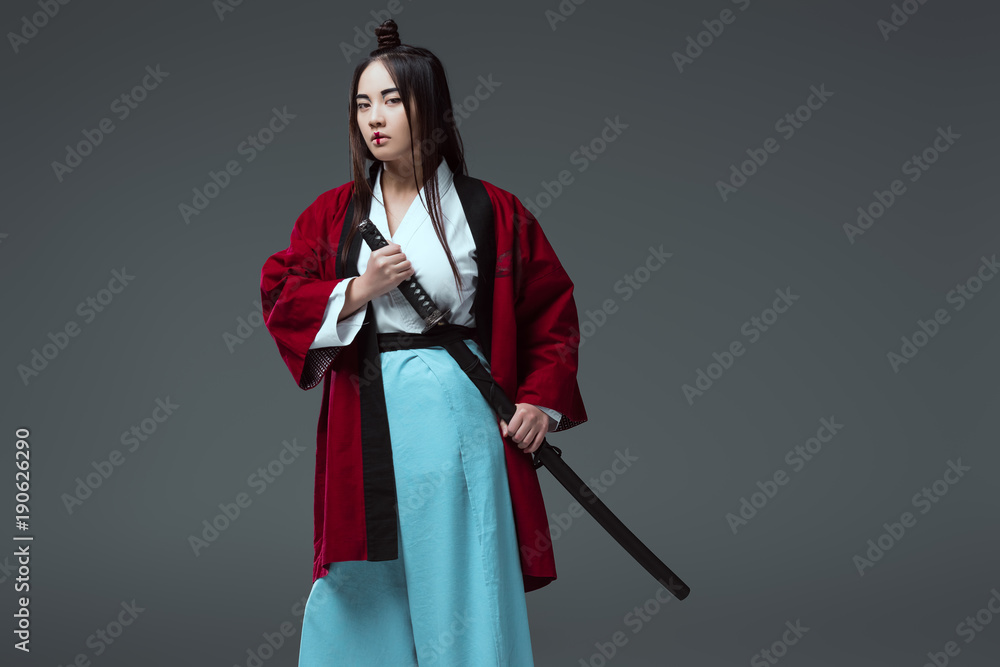 young asian woman in kimono holding katana sword and looking at camera  isolated on grey Stock Photo | Adobe Stock